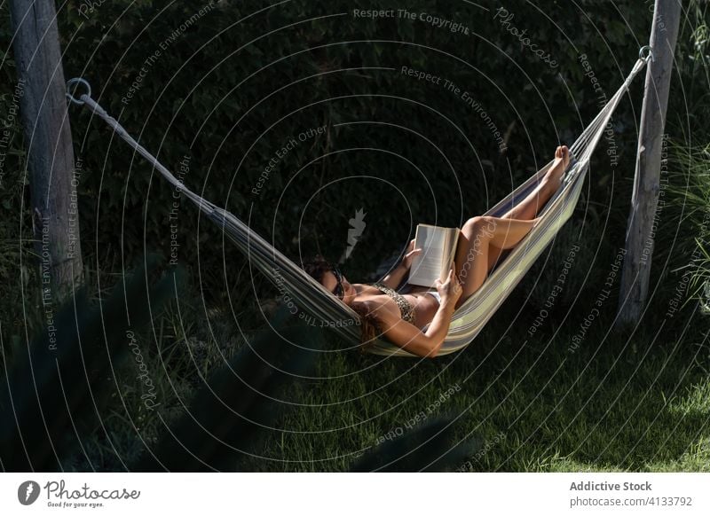 Entspannte Frau mit in Hängematte liegendem Buch sich[Akk] entspannen Kälte Sommer ruhen lesen Lügen Garten Feiertag Urlaub Erholung Lifestyle ruhig genießen
