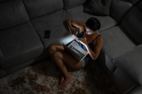 Zufriedene Frau am Computer im Wohnzimmer heimwärts Abend Inhalt Laptop Kaffee benutzend Tasse heimisch Teppich Technik & Technologie Browsen Apparatur Internet