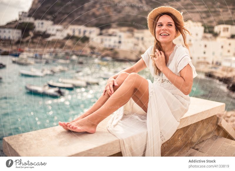 Entzückte reisende Frau auf Steinbrüstung in der Bucht Urlaub hafen Reisender Freude Brüstung Tourist Feiertag Boot levanzo Insel Sommer Glück Zaun Lächeln