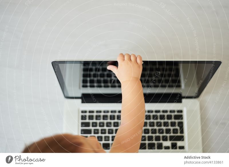 Anonymes Baby spielt mit Laptop zu Hause benutzend Draufsicht anonym heimwärts spielen Kleinkind Apparatur modern Kindheit Lifestyle wenig allein heiter Gerät