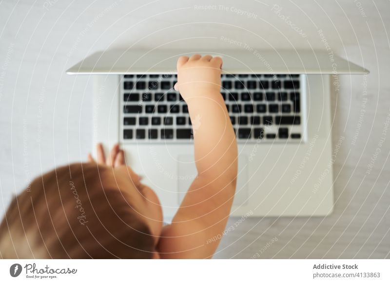 Anonymes Baby spielt mit Laptop zu Hause benutzend Draufsicht anonym heimwärts spielen Kleinkind Apparatur modern Kindheit Lifestyle wenig allein heiter Gerät