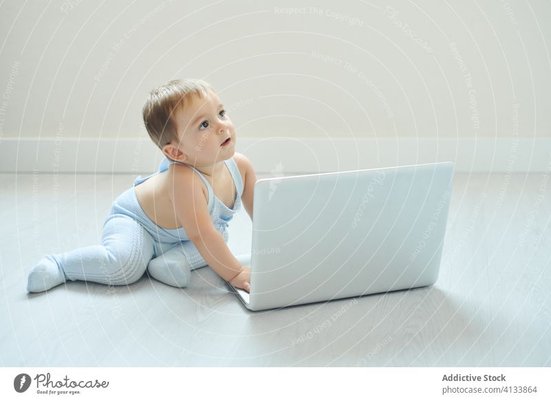 Fröhliches Baby spielt zu Hause mit dem Laptop Glück benutzend heimwärts spielen Kleinkind Apparatur modern Kindheit Lifestyle wenig allein heiter Gerät Netbook