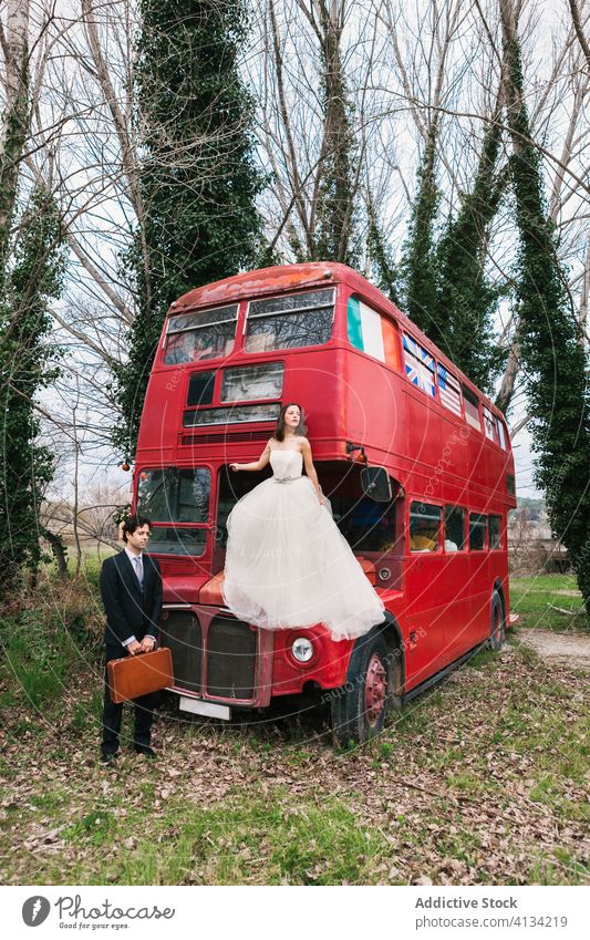 Frischvermähltes Paar in der Nähe eines verlassenen roten Busses im Wald Jungvermählter roter Bus Hochzeit Doppeldeckerbus Braut striegeln Verlassen Holz