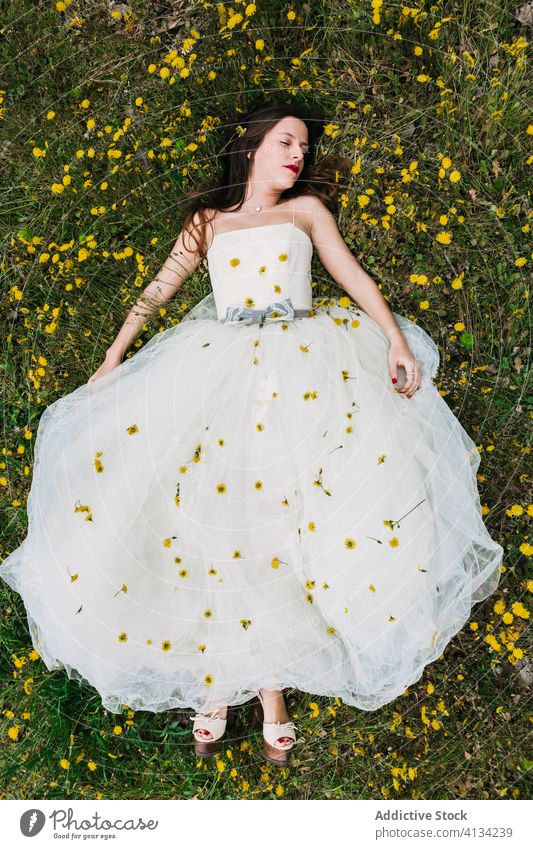 Entspannte Braut liegt mit Blumen auf der Wiese Lügen striegeln Streicheln sich[Akk] entspannen Löwenzahn Jungvermählter Frau Blüte Zusammensein Hochzeit Rasen
