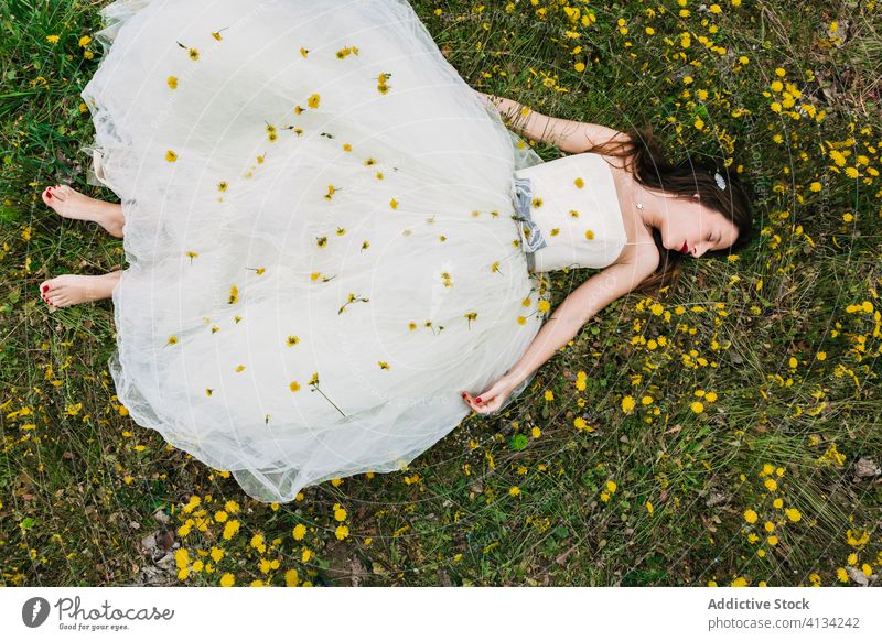 Entspannte Braut liegt mit Blumen auf der Wiese Lügen striegeln Streicheln sich[Akk] entspannen Löwenzahn Jungvermählter Frau Blüte Zusammensein Hochzeit Rasen