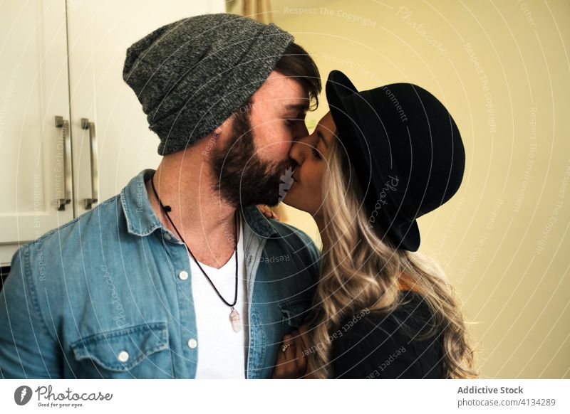 Glückliches Paar umarmt sich beim Kaffeetrinken zu Hause Kuss Partnerschaft positiv Hipster Stil Freund Zuneigung Zusammensein Umarmen Küche Liebe Freundin