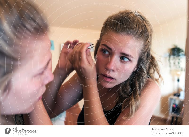 Junge Frau, die ihre Augenbrauen mit einer Pinzette korrigiert rupfen richtig Schönheit Spiegel heimwärts lässig Zange Pflege Routine jung Leckerbissen