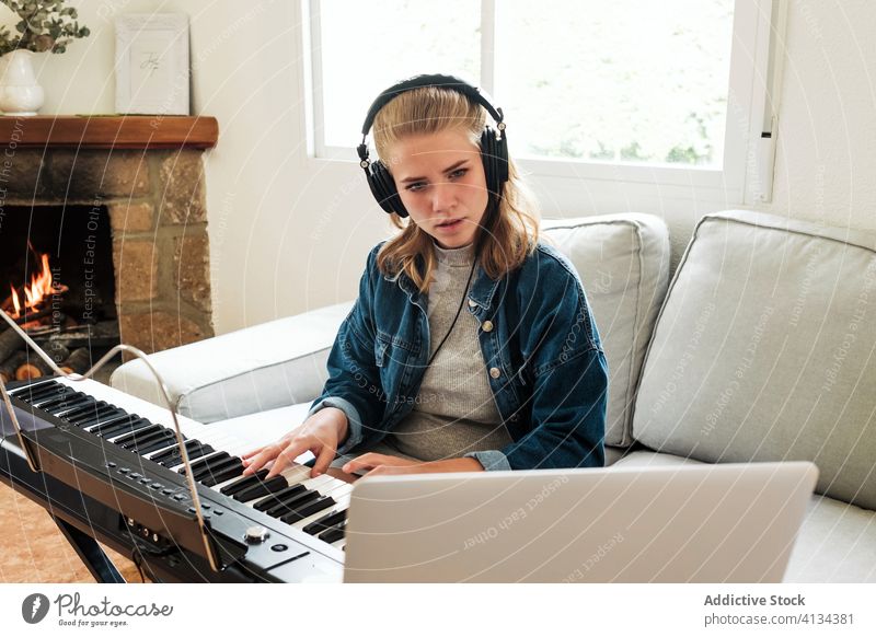 Junge Frau spielt Synthesizer zu Hause spielen Klavier lernen online heimwärts Musik elektronisch Musiker Laptop Tutorial jung Komponist modern Gerät Apparatur