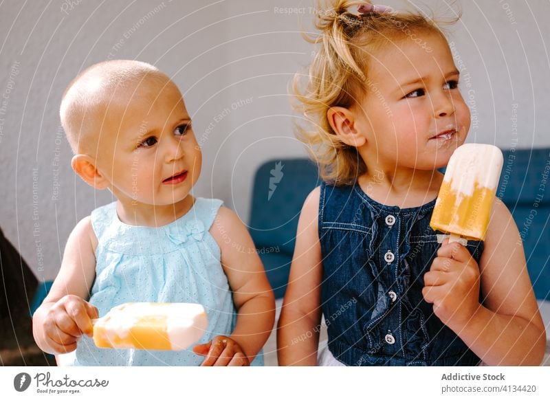 Zufriedene Schwestern essen selbstgemachte Eislutscher auf der Terrasse Stieleis Kies Mädchen Kind Zusammensein lecker Kleinkind wenig süß niedlich Hof