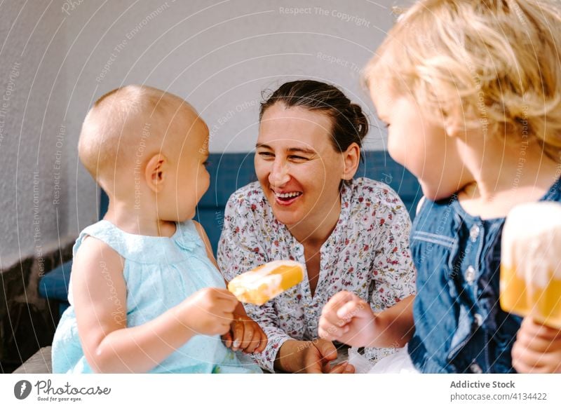 Freudige Großmutter und kleine Mädchen essen Eis auf der Terrasse Stieleis Speiseeis genießen Enkelin Zusammensein Hof selbstgemacht Freude wenig Frau heiter