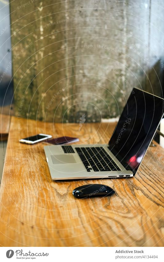 Laptop auf einem Holztresen in einem Cafe Netbook Café Tisch modern gemütlich Apparatur Kaffeehaus Anschluss hölzern Maus Gerät Smartphone Mobile Internet