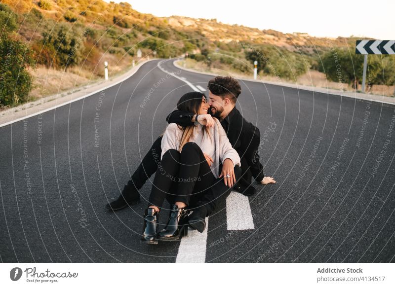 Junges verliebtes Paar auf der Straße sitzend Liebe Umarmen sanft Zusammensein Glück jung Partnerschaft romantisch Fahrbahn Umarmung Abenteuer Ausflug genießen