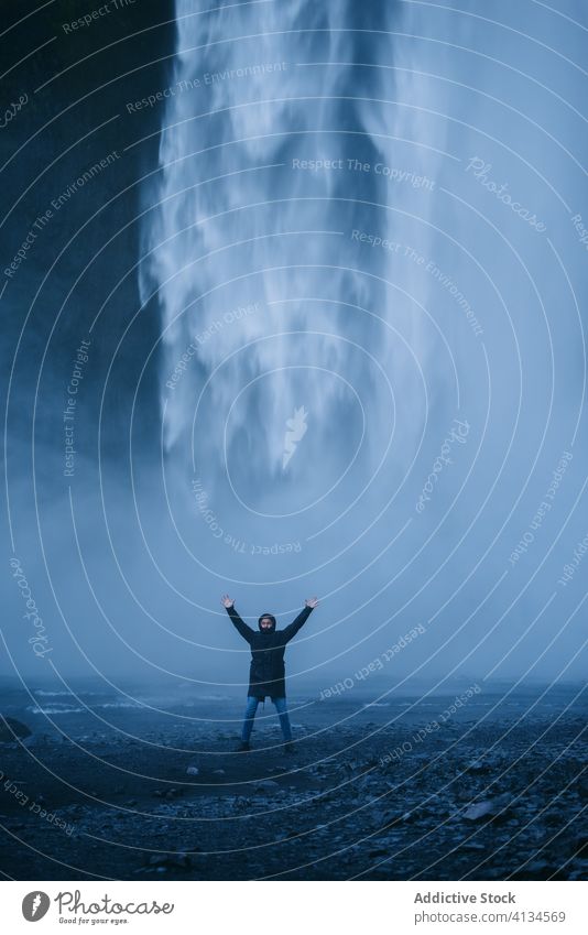 Aufgeregter männlicher Reisender in der Nähe eines mächtigen Wasserfalls Mann aufgeregt genießen Kraft Urlaub Oberbekleidung kalt Natur Tourismus Island Tourist