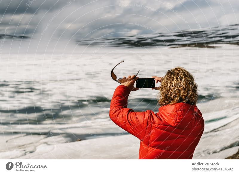 Reisender, der einen zugefrorenen See fotografiert reisen fotografieren Mann Smartphone benutzend Tourist Oberbekleidung kalt männlich Island spektakulär