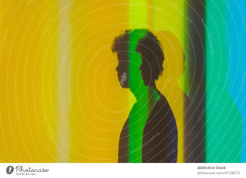 Anonymer Mann in kreativem bunten Studio neonfarbig Licht farbenfroh Schatten Atelier Kunst Farbe lebhaft männlich pulsierend mehrfarbig stehen Stil hell