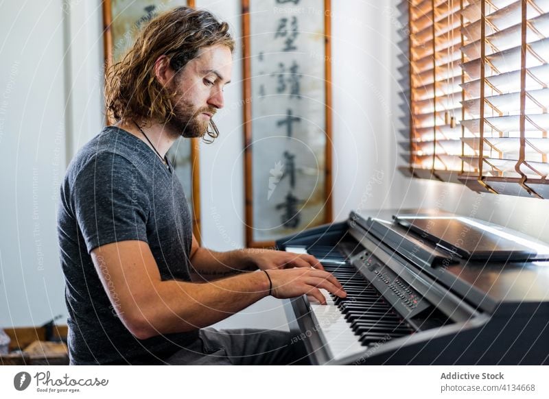 Talentierter Mann spielt zu Hause Klavier spielen Synthesizer Musiker Instrument heimwärts elektronisch männlich Fähigkeit Appartement gemütlich sitzen Melodie