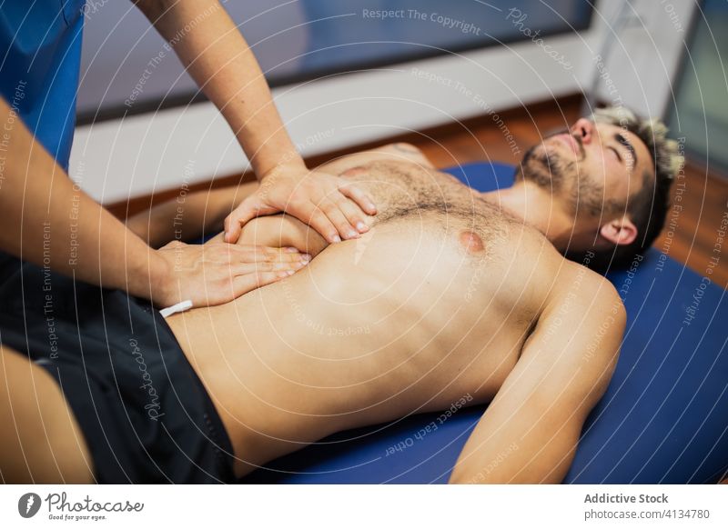 Unkenntlich gemachter Orthopäde massiert den Brustkorb eines fitten Patienten in der Klinik Osteopath Massage geduldig untersuchen Unterstützung Spezialist