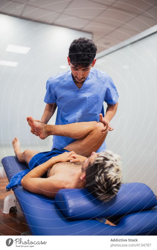Orthopäde beugt das Bein eines Sportlers während einer medizinischen Untersuchung geduldig Wiederherstellung untersuchen Knie professionell Osteopathie