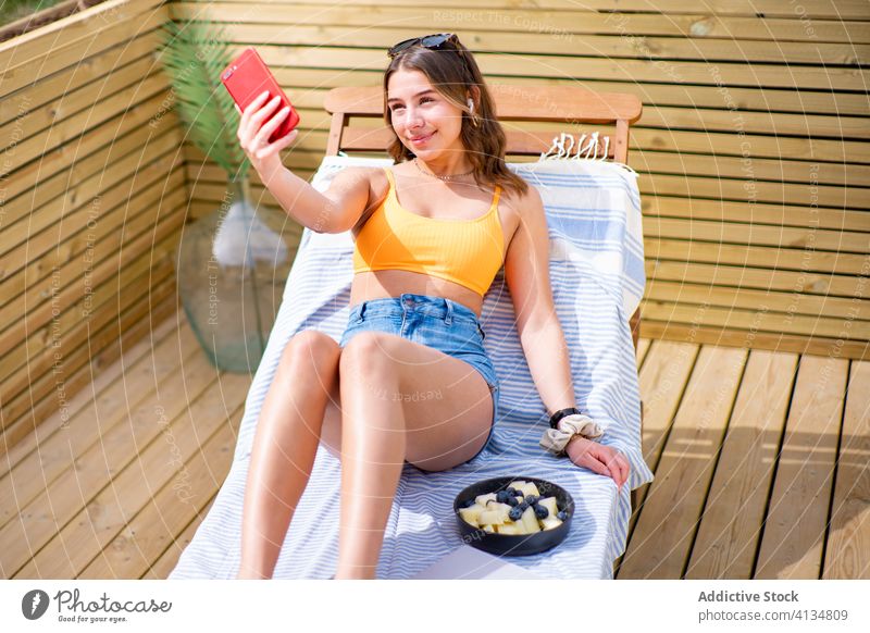 Charmante Frau nimmt Selfie auf Smartphone auf Liegestuhl Sommer positiv sonnig Fotokamera sich[Akk] entspannen benutzend charmant Shorts BH Lügen Funktelefon