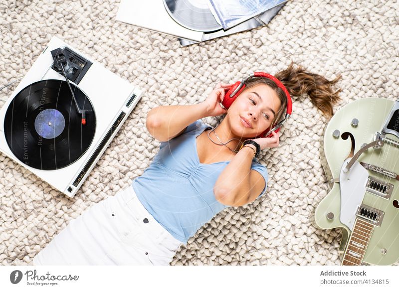 Entspannte Frau mit Kopfhörern, die Musik von einer Schallplatte hört zuhören Vinyl Aufzeichnen Scheibe heimwärts ruhen Kälte Glück sich[Akk] entspannen Lächeln