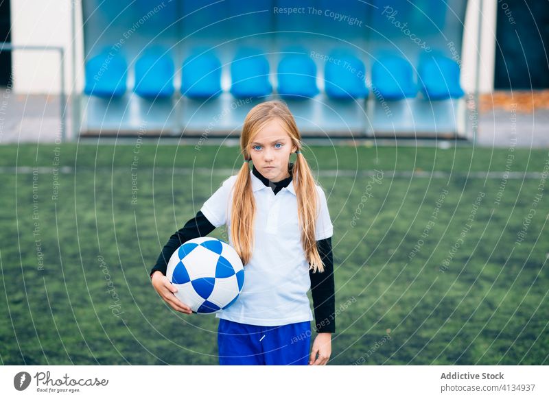 Ernsthafte junge Spielerin mit Ball in einer Fußballarena im Sportstadion Mädchen Feld Uniform Kind Club Kindheit Athlet Gerät Schulmädchen heiter Trikot Frau