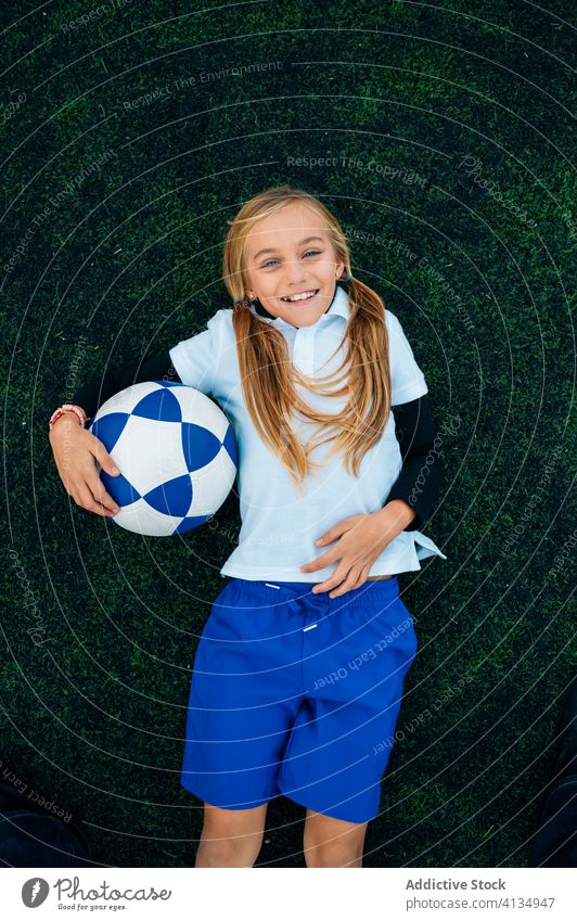 Fröhliche Spielerin mit Fussball entspannt auf dem Rasen Mädchen Fußball Lachen Feld sich[Akk] entspannen Ball Pferdeschwanz Stadion Kind Glück spielerisch
