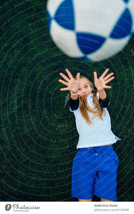 Zufriedene junge Spielerin wirft den Ball hoch, während sie auf dem Fußballfeld liegt Mädchen werfen Spaß haben ruhen Feld Kind Stadion sich[Akk] entspannen