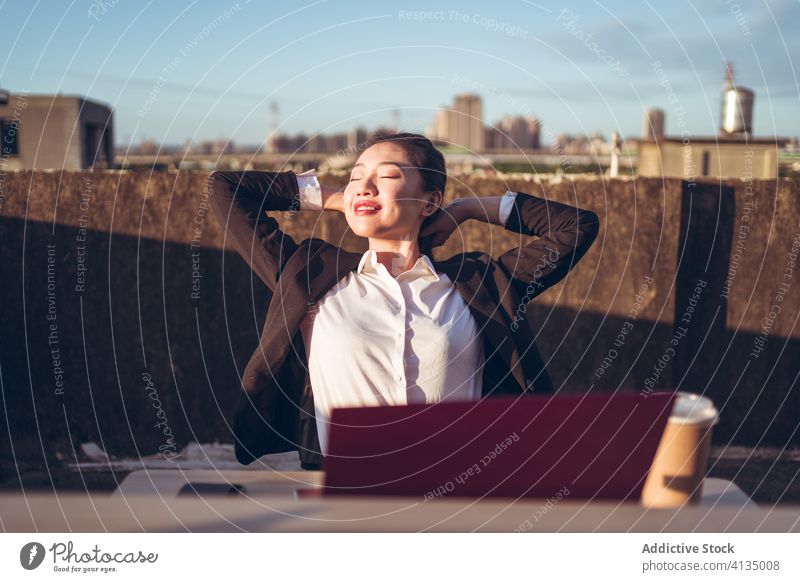 Fröhliche Frau hat Pause während Fernarbeit mit Laptop sich[Akk] entspannen beschäftigt Arbeit ruhen Dachterrasse Arbeitsplatz jung asiatisch Mitarbeiter