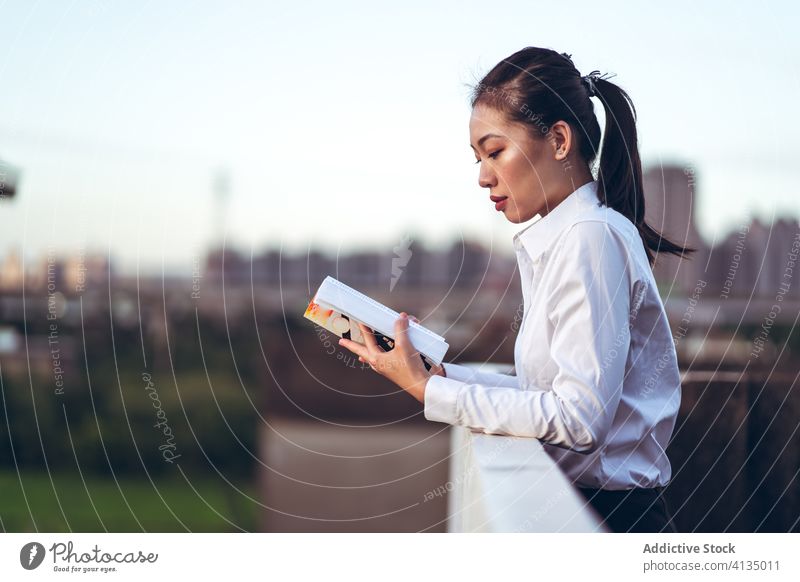 Junge beschäftigte Frau liest Buch auf dem Dach lesen Geschäftsfrau Dachterrasse modern jung formal urban Pause ruhen asiatisch ethnisch Lifestyle klug