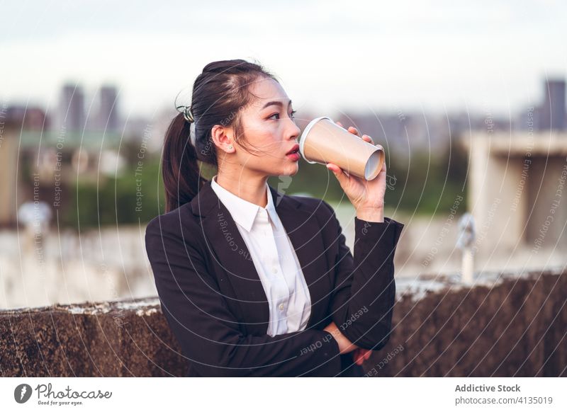 Junge Geschäftsfrau trinkt einen Kaffee zum Mitnehmen ernst Fokus Frau Imbissbude Pause jung asiatisch ethnisch formal Einwegartikel Tasse Dachterrasse trinken