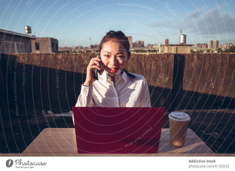 Geschäftige Frau mit Laptop arbeitet auf dem Dach Arbeit Smartphone benutzend reden Geschäftsfrau formal Dachterrasse Gerät Apparatur Business asiatisch jung