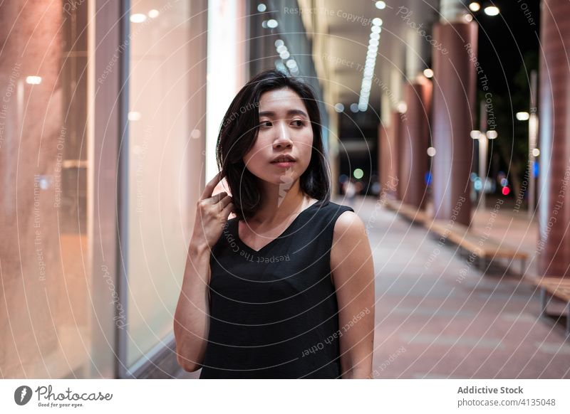 Asiatische Frau auf der Straße bei Nacht Bürgersteig Abend Gebäude leuchten schlendern Großstadt Straßenbelag asiatisch ethnisch urban Stil Freude lässig trendy