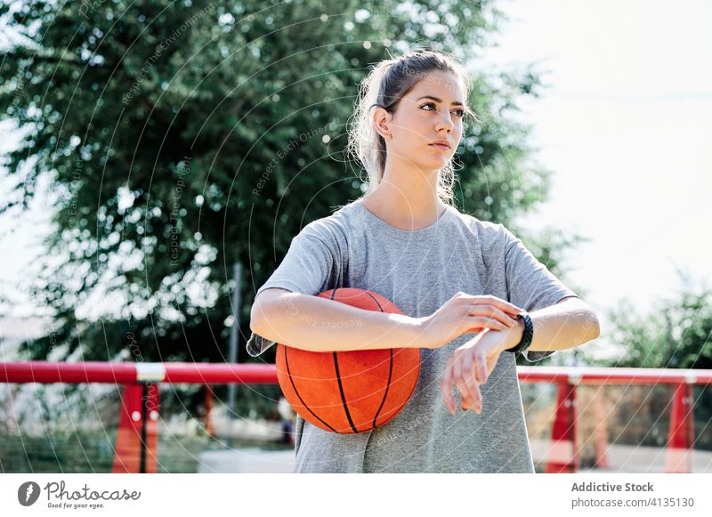 Sportliche Frau mit Basketball wartet auf Freund Ball warten Zeit prüfen Armbanduhr Gericht ernst jung Sportlerin Athlet spät Verzögerung Training Aktivität