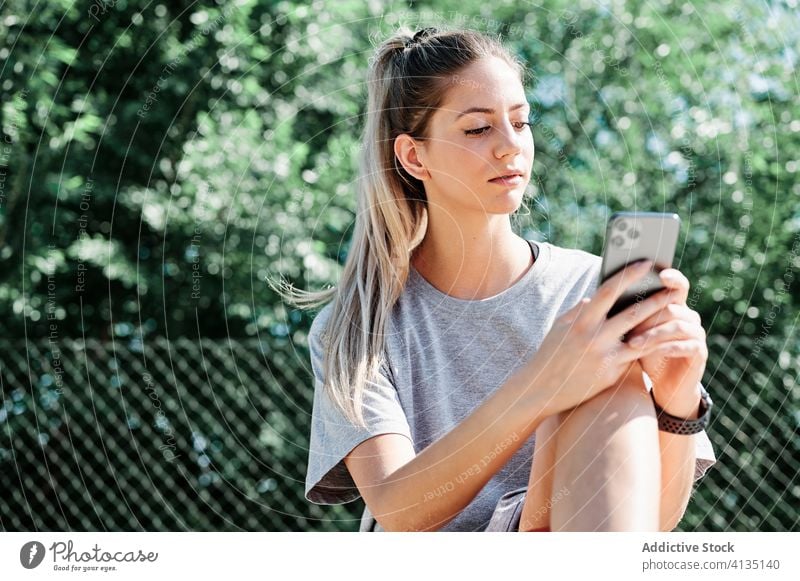 Sportlerin mit Basketball-Ball und Smartphone auf dem Spielplatz Frau benutzend Gericht ernst jung ruhen Browsen Telefon Mobile Athlet Training Aktivität