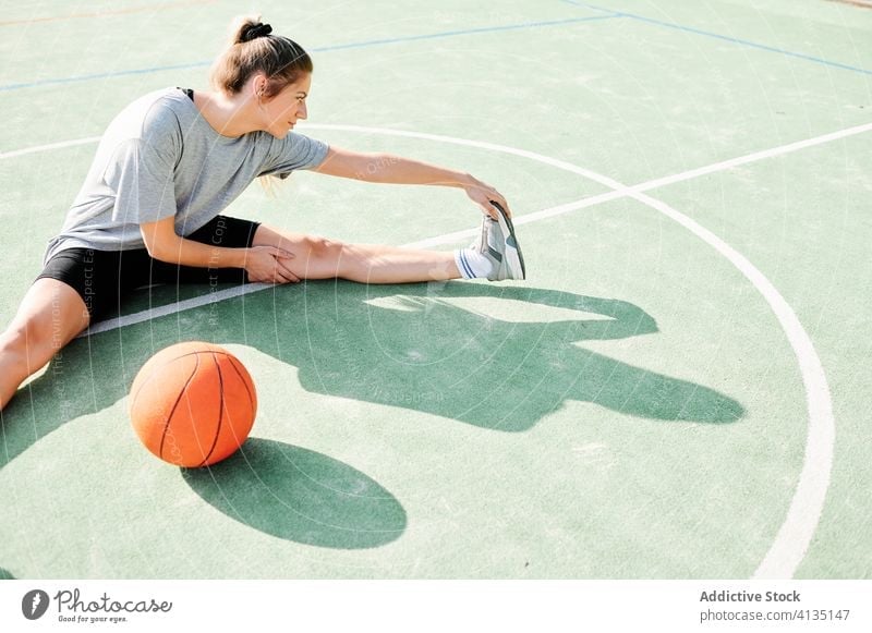 Basketballspielerin beim Stretching auf dem Sportplatz Frau Dehnung Übung Aufwärmen Sportpark Training vorbereiten Spieler Ball Gericht Aktivität Lifestyle