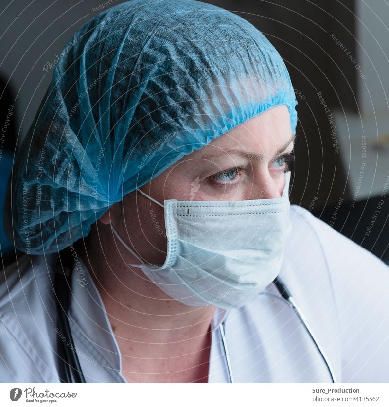 Medizinische Frau Gesicht Nahaufnahme. Arzt in einer medizinischen Maske und Kittel. Sie sieht müde aus. Sie schaut aus dem Fenster. Horizontale Komposition