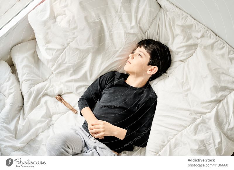 Ruhiger Junge auf weißer Decke liegend Kind heimwärts träumen Vorstellungskraft Windstille genießen Wochenende Bett weich gemütlich Fenster ruhig Gelassenheit
