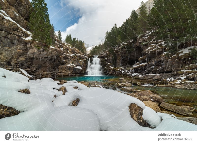 Wasserfall mit Pool zwischen schneebedeckten Bergen Berge u. Gebirge Schnee Wald Natur Landschaft Winter wild strömen malerisch Umwelt Felsen Harmonie kalt