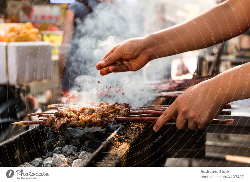 Männlicher Koch bereitet Kebab auf dem Grill zu Mann Grillrost Spieß vorbereiten Prozess Gewürz hinzufügen Fleisch männlich lecker Lebensmittel Mahlzeit Speise