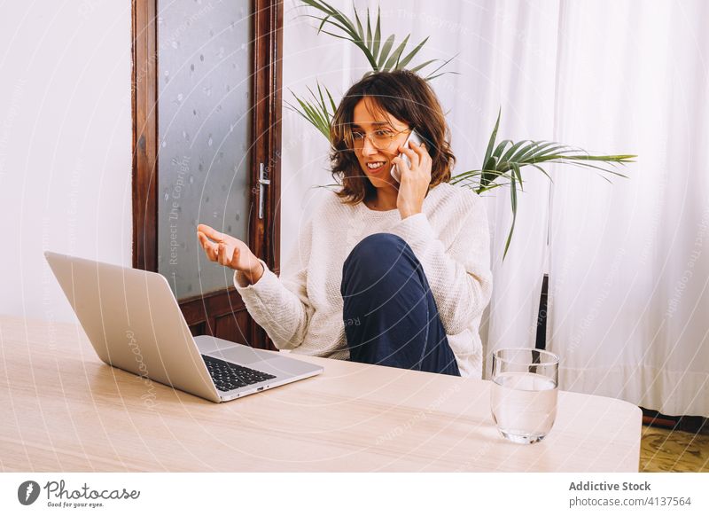 Junge Frau bei der Arbeit mit Gadgets zu Hause heimwärts Smartphone benutzend Laptop lässig Fokus Telefon Nachricht jung freiberuflich Lifestyle Beruf Gerät