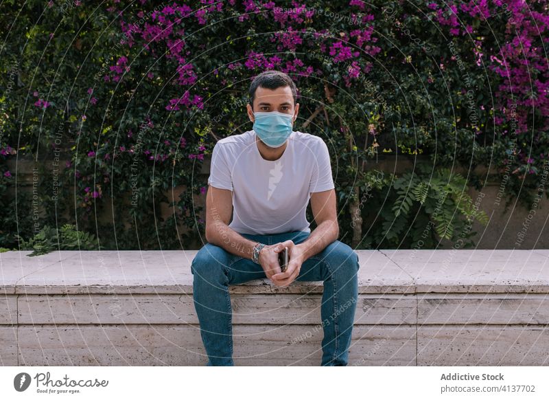 Junger Mann trägt während einer Pandemie eine Gesichtsmaske im Freien Straße Mundschutz Korona Virus Schutz jung Großstadt Person Krise beunruhigt Entfernung