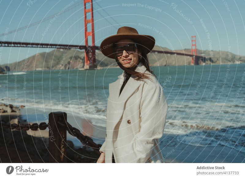 Stilvolle Frau am Wasser stehend mit Brücke im Hintergrund trendy reisen Glück Lächeln jung genießen Tourismus San Francisco Goldenes Tor Kalifornien amerika