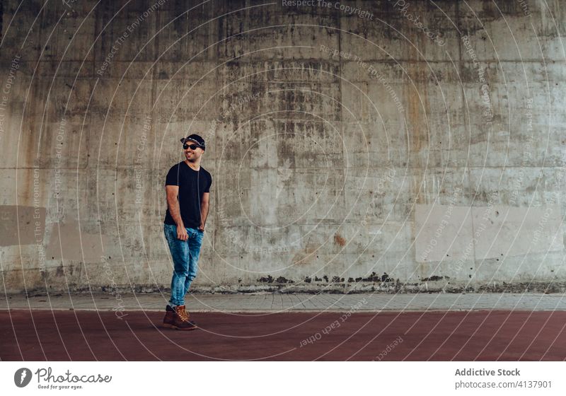 Junger Hipster Mann steht in der Nähe von Gebäude jung Stil selbstbewusst trendy modern Wand Beton schäbig Glück männlich gutaussehend Typ lässig Vollbart