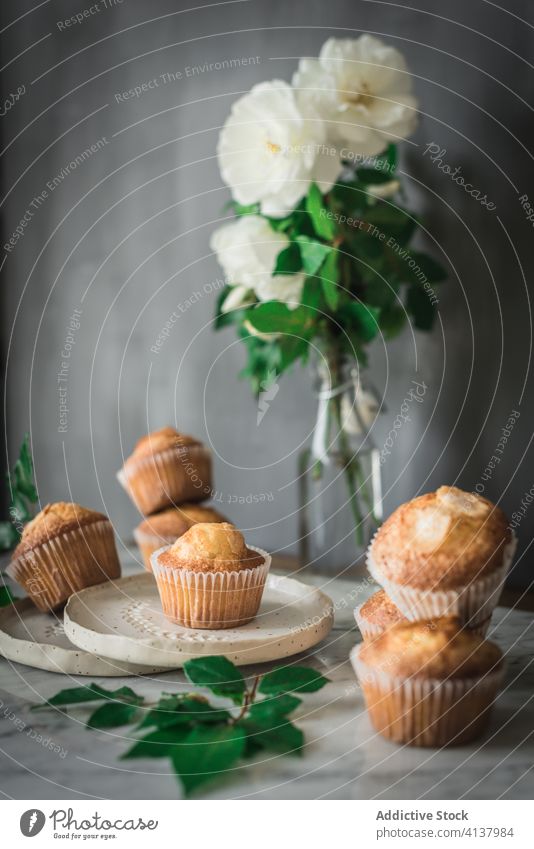 Köstliche Törtchen in Komposition mit duftenden weißen Blumen in Vase auf dem Tisch Cupcake Lebensmittel Leckerbissen Roséwein Mahlzeit Dessert Blumenstrauß