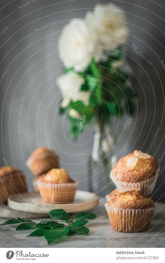 Köstliche Törtchen in Komposition mit duftenden weißen Blumen in Vase auf dem Tisch Cupcake Lebensmittel Leckerbissen Roséwein Mahlzeit Dessert Blumenstrauß