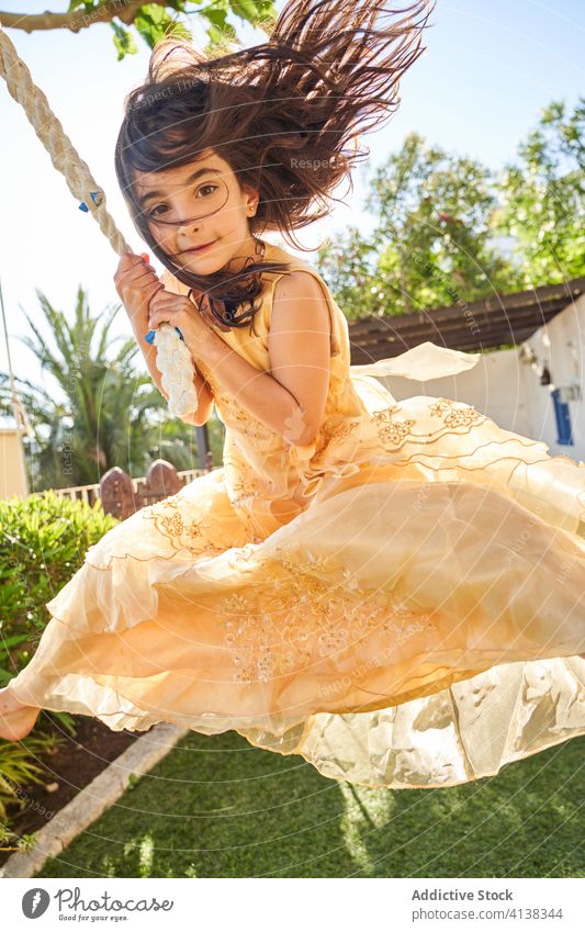 Kleines Mädchen im Kleid schwingt an einem Seil pendeln Kind Glück Garten Sommer Spaß haben Urlaub Feiertag frei Lächeln charmant positiv Aktivität heiter