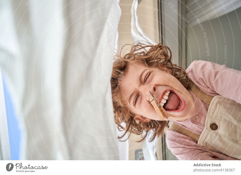 Fröhlicher kleiner Junge mit Wäscheklammer an der Nase schreien Kleiderspin Spaß Wäscherei Stecknadel Zapfen so tun, als ob Witz Humor Kind heimwärts Kindheit