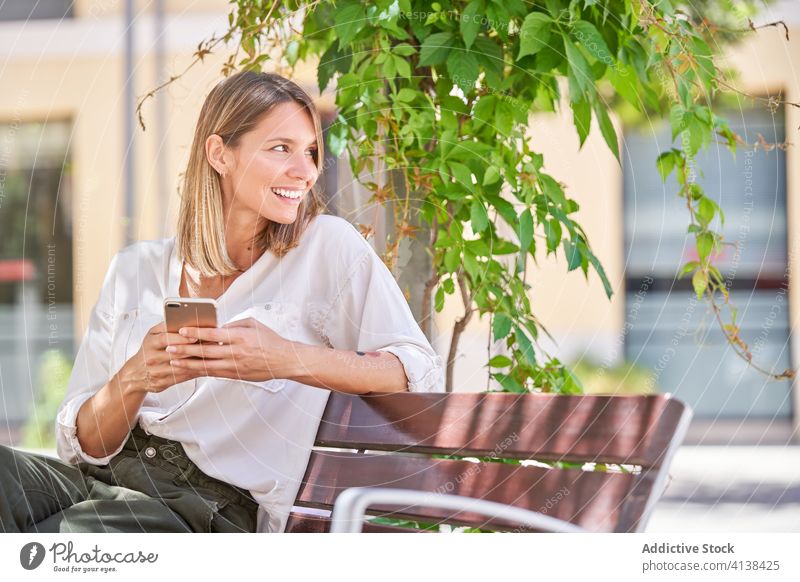 Stilvolle Frau mit Handy chillen auf Bank im Sommer Tag Smartphone Lifestyle benutzend Texten modern Kälte ruhen Gerät Apparatur Anschluss Mobile Kommunizieren