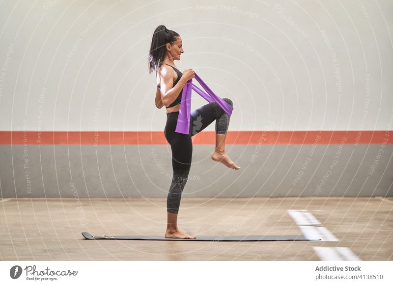 Flexible Sportlerin beim Training mit Gummiband im Fitnessstudio widersetzen Band elastisch Dehnung beweglich Übung Frau heiter Sportkleidung Barfuß Unterlage