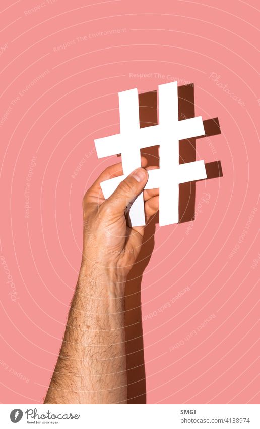 Die Hand eines Mannes hält eine weiße Raute auf einem rosa Hintergrund. Website Medien sozial Marketing männlich Gefolgsleute vereinzelt Netzwerk Tag